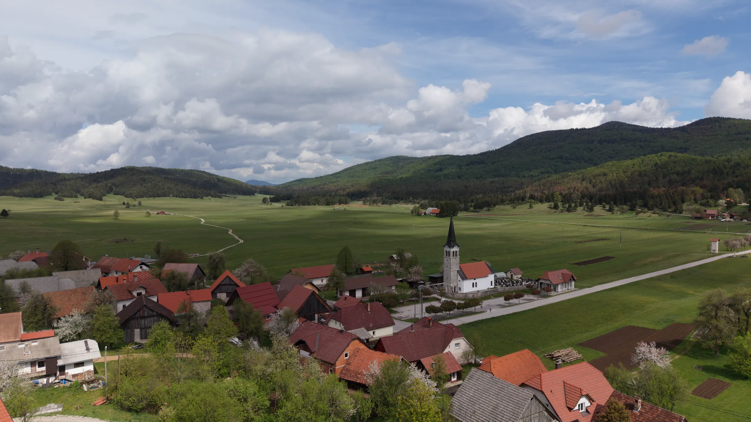 Vas Babno Polje iz zraka - cerkev, travniki in gozdovi Notranjske